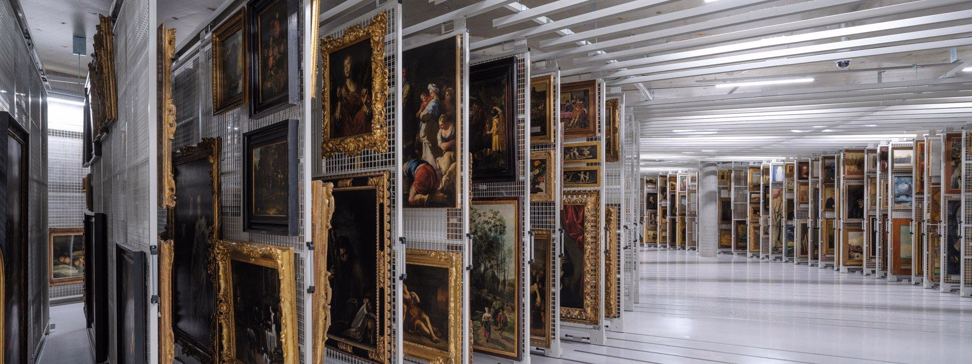 The vault beneath the museum — archive storage with artworks on display racks