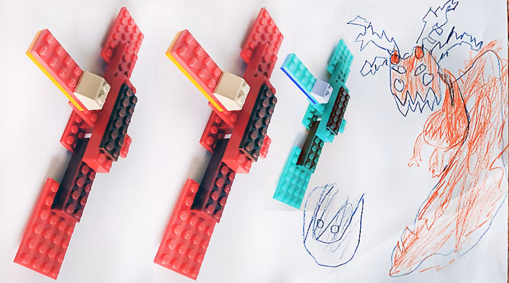 Two red Lego pieces and one teal one beside a red and blue crayon drawing of a creature.