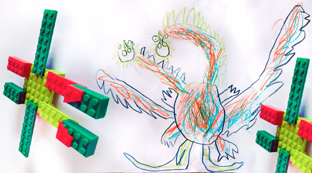 A green Lego cross shape beside a looping crayon drawing of a bird-like creature.