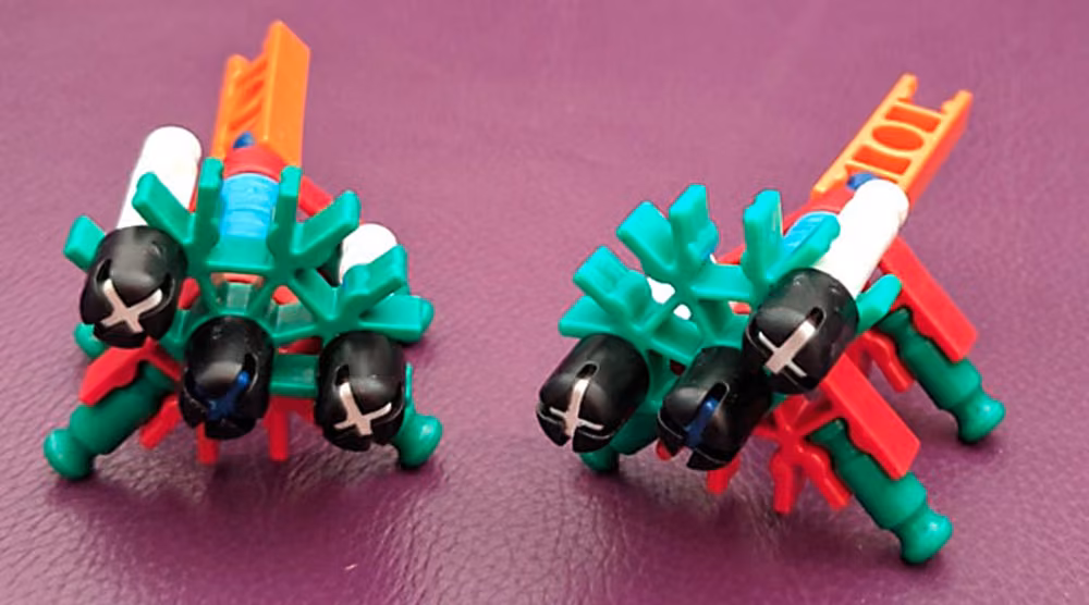 Two matching K&rsquo;nex constructions in green, white and red on a purple surface.