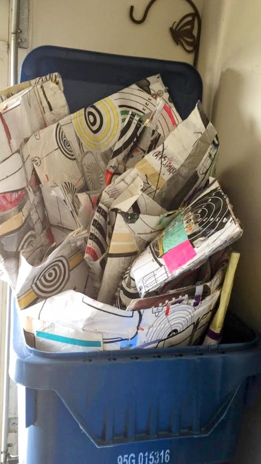 A discarded artwork standing in a trash can, photographed in black and white.